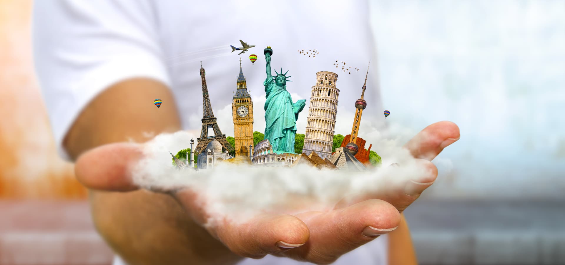 Hand holding a cloud of iconic world landmarks including the Eiffel Tower, Big Ben, Statue of Liberty, and Leaning Tower of Pisa