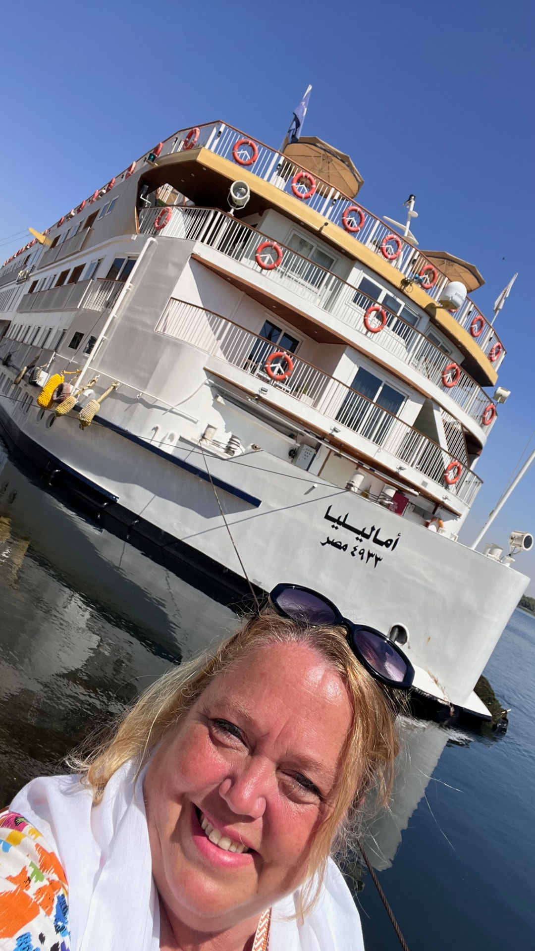 Christine smiling in front of the Amaliyah river ship moored on the Nile in Egypt