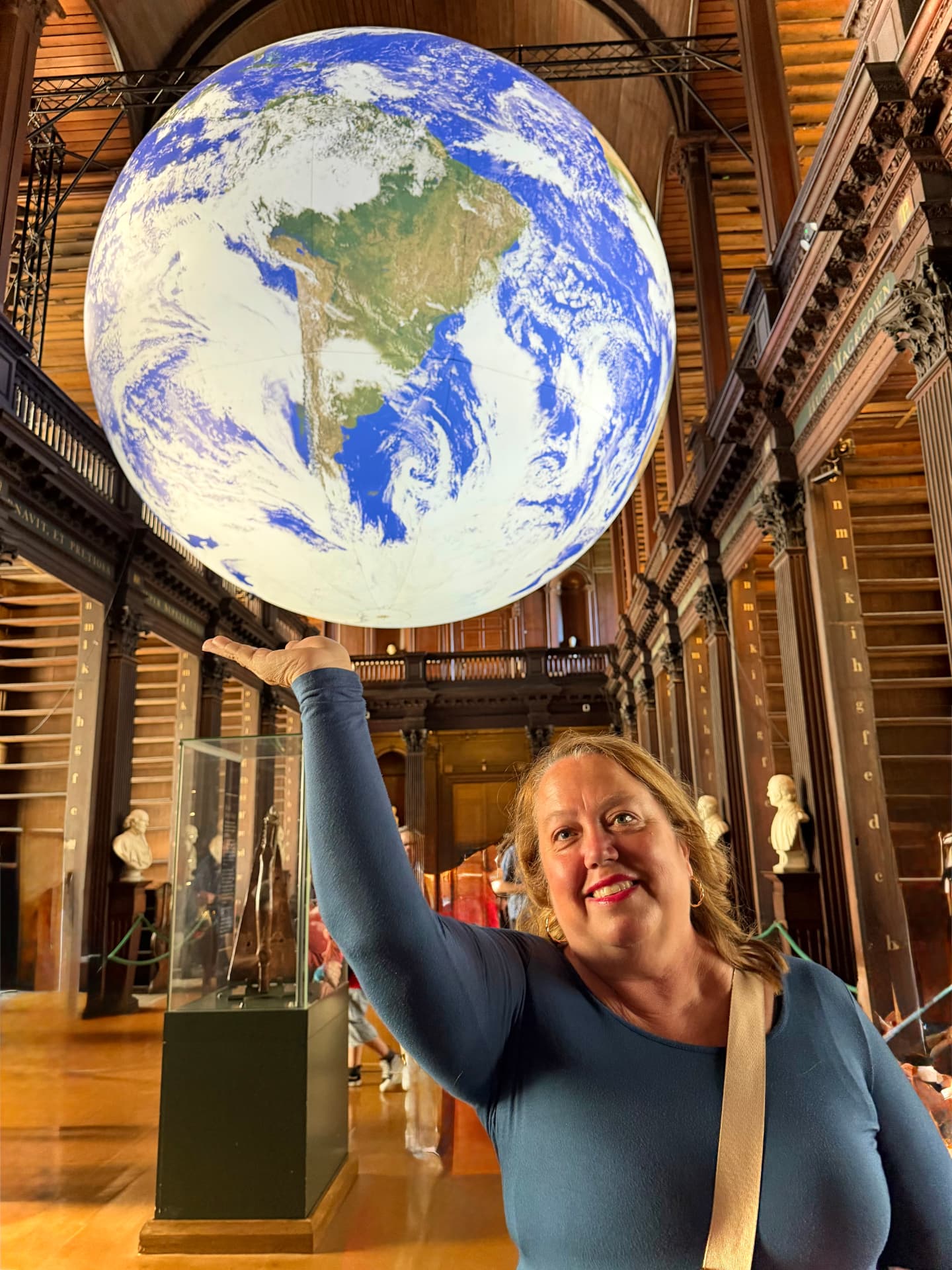 Christine Scheeler pointing up at the illuminated globe in the Long Room library at Trinity College Dublin.