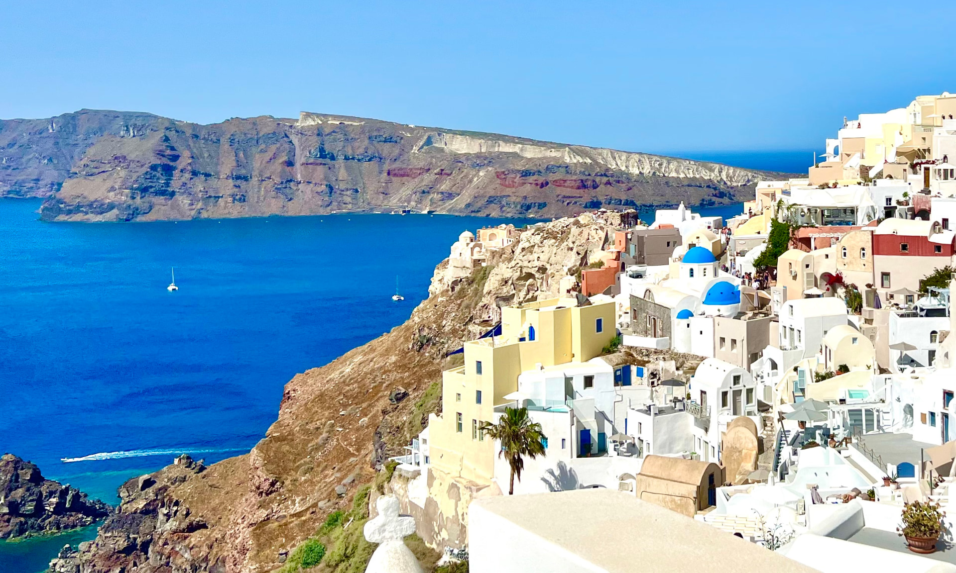 Santorini caldera view with blue-domed churches and whitewashed cliffside buildings at sunset