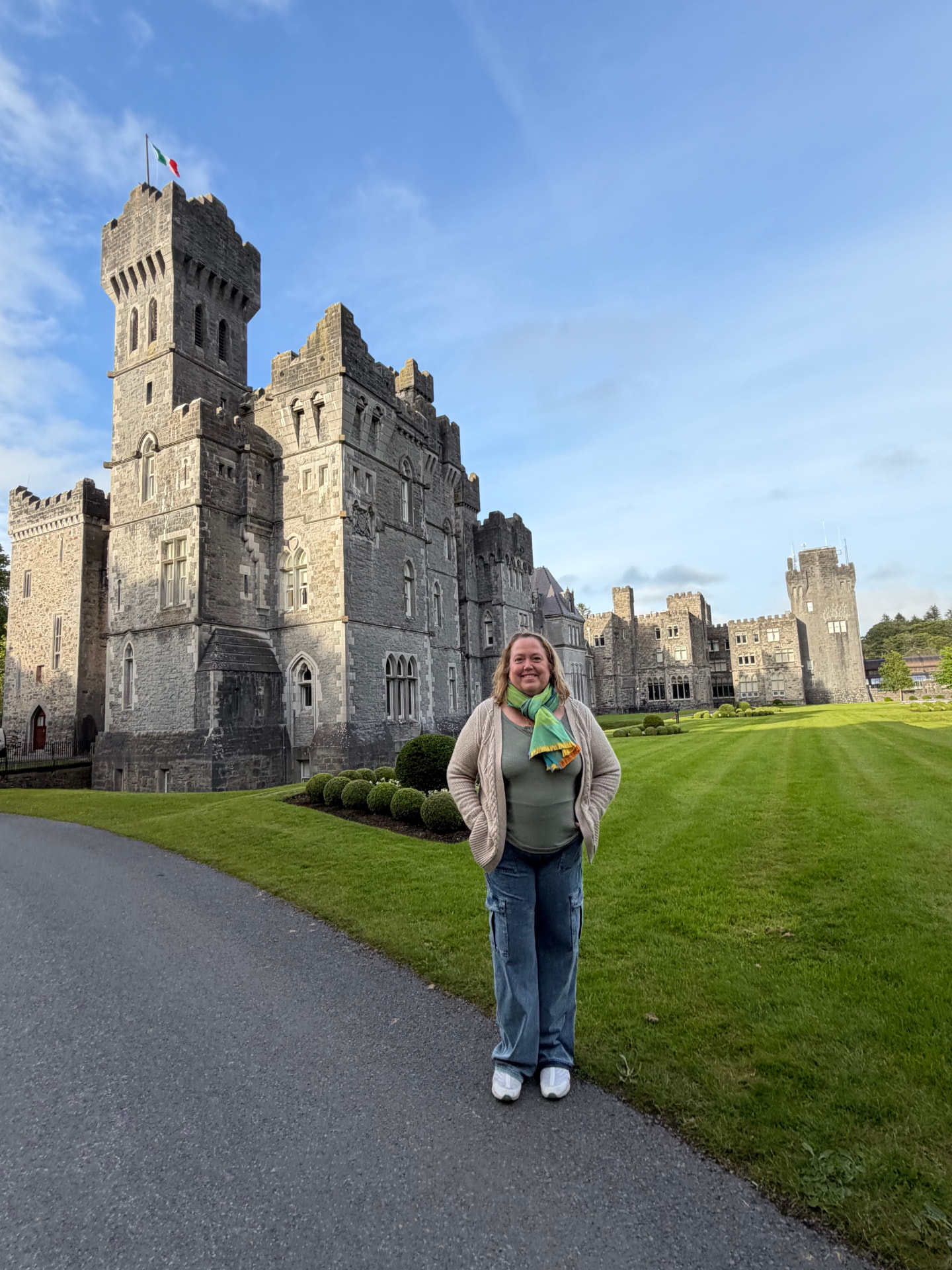 Christine standing on the manicured lawn in front of Ashford Castle in Ireland