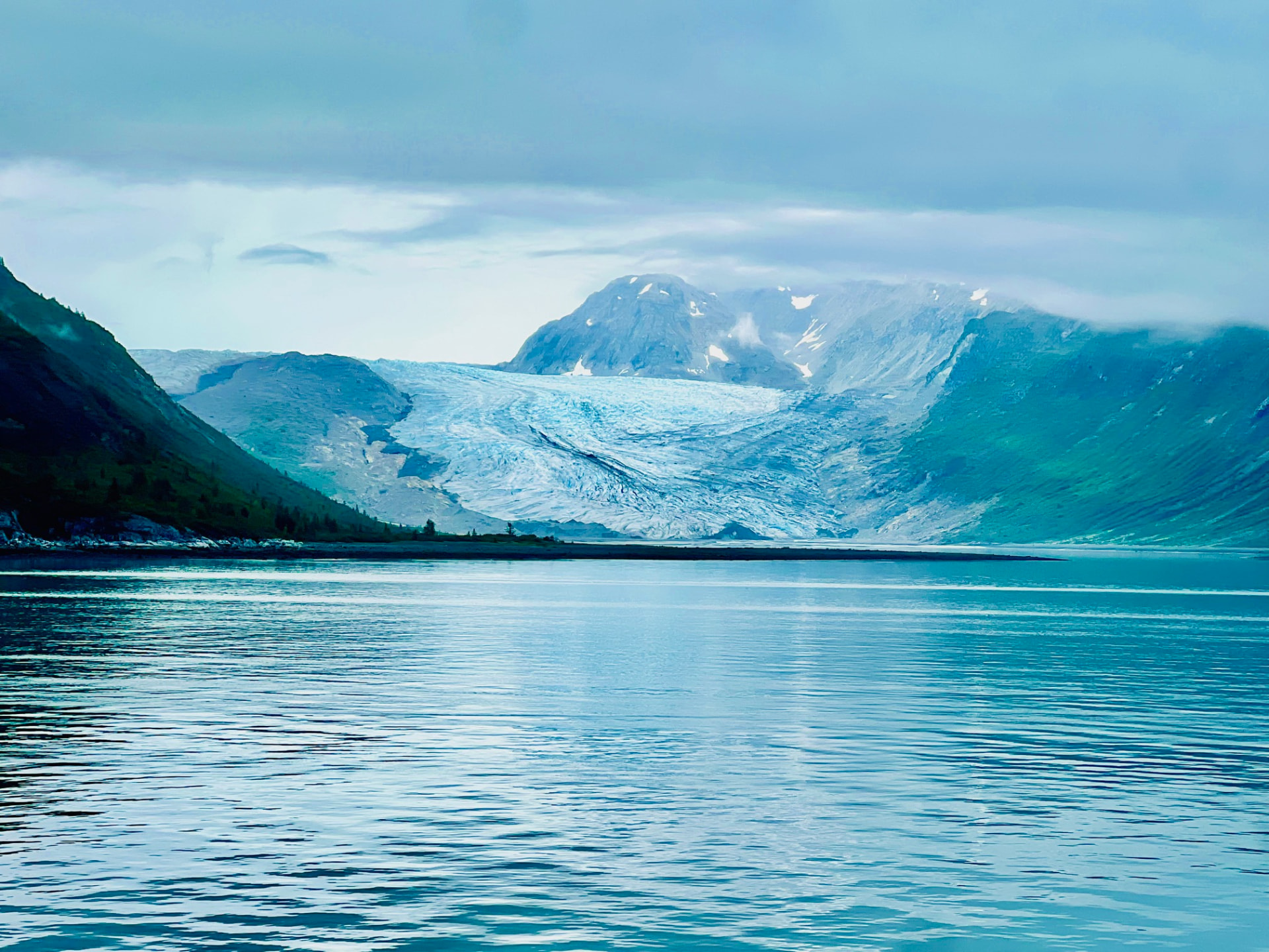A glacier descending into calm water in Glacier Bay National Park, Alaska.