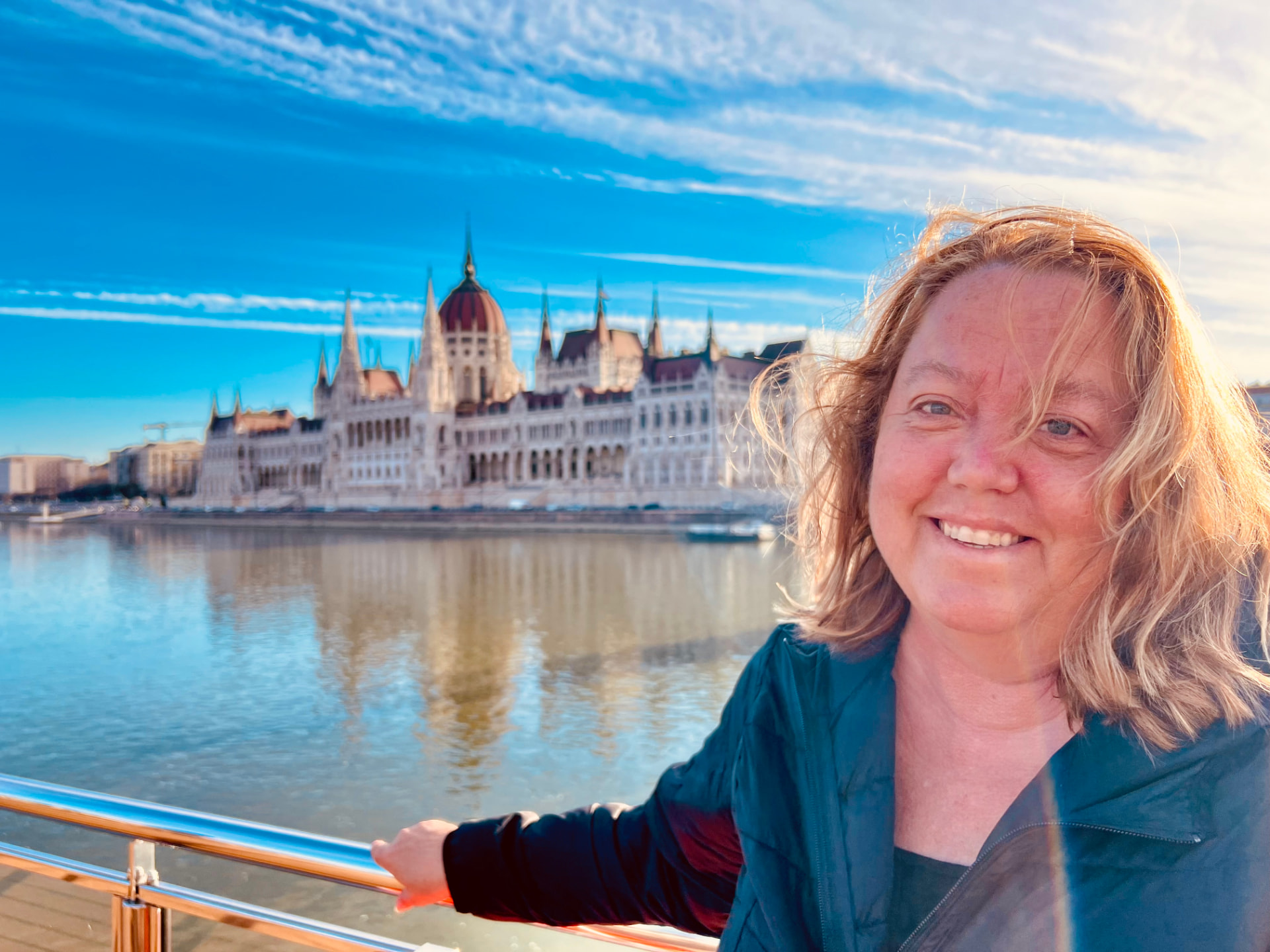 Christine on a river cruise ship deck at golden hour with the Hungarian Parliament building across the Danube in Budapest