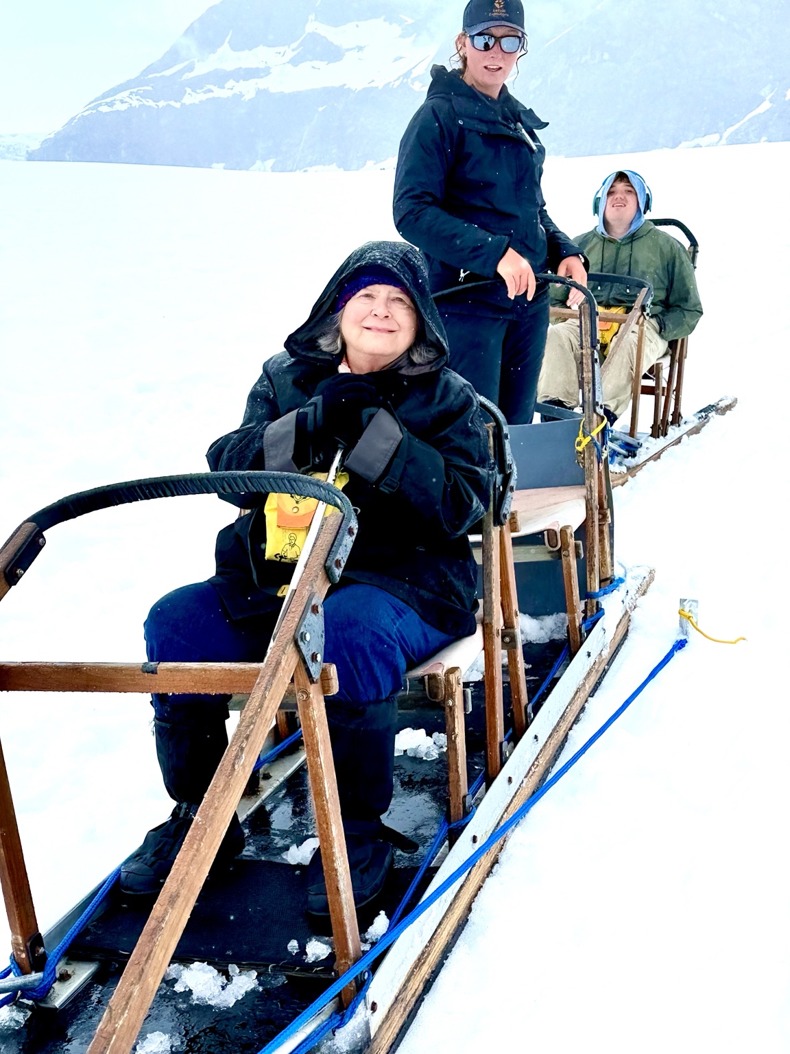 A musher guides a dog sled carrying my mother and son across the snow on the Juneau Icefield