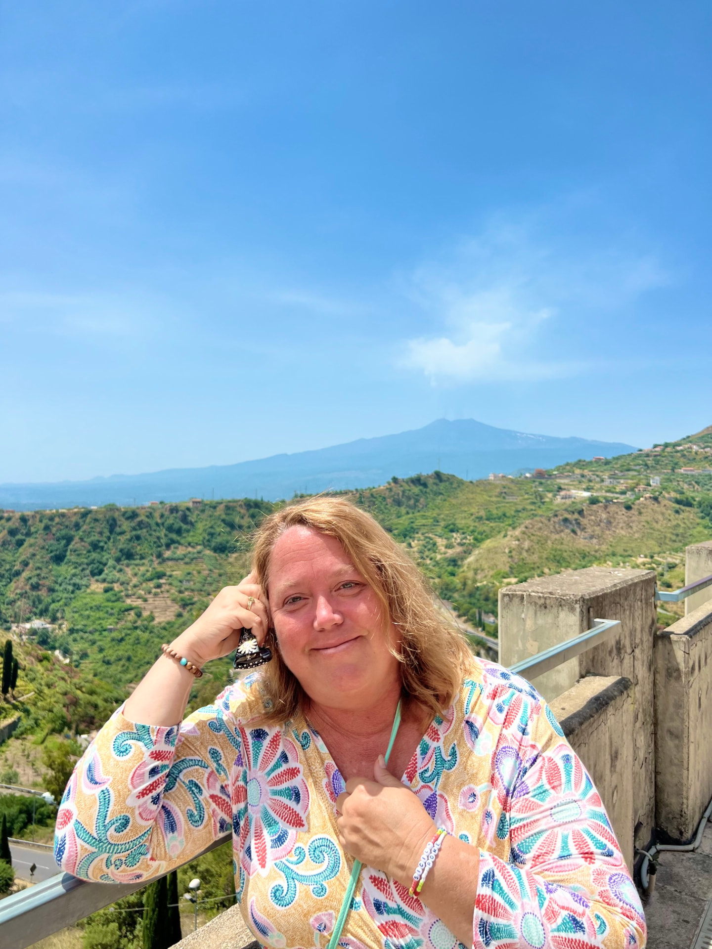 Christine Scheeler on a balcony in Taormina, Sicily, with Mount Etna in the background