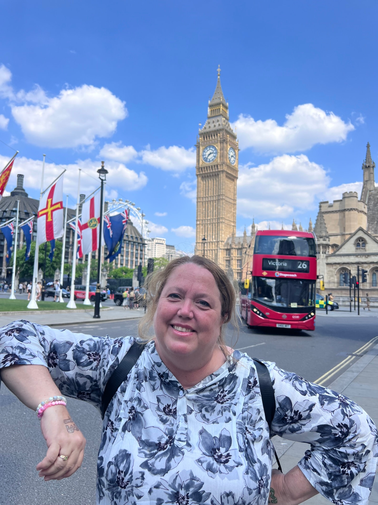Christine Scheeler smiling in Parliament Square with Big Ben, flags, and a red double-decker bus behind her