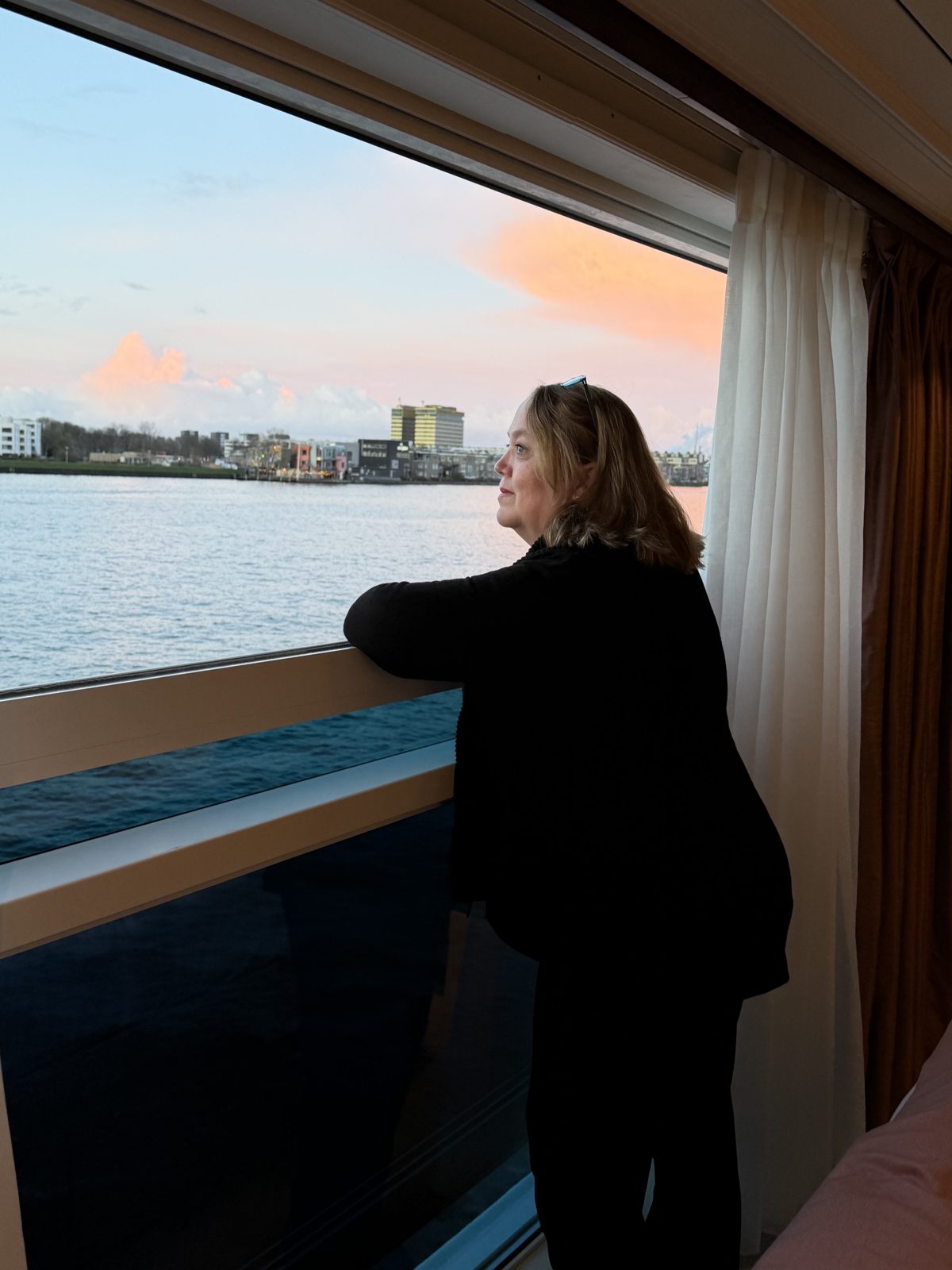 Christine Scheeler looking out a large window aboard Uniworld's S.S. Emilie at sunset